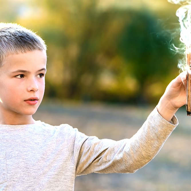 male child holding a smoking stick