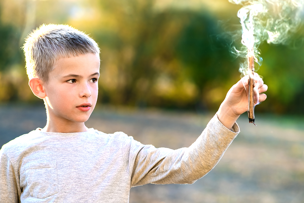 male child holding a smoking stick