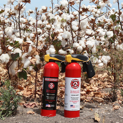 two fire extinguishers in front of a cotton field