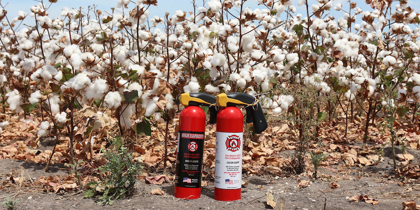 two fire extinguishers in front of a cotton field